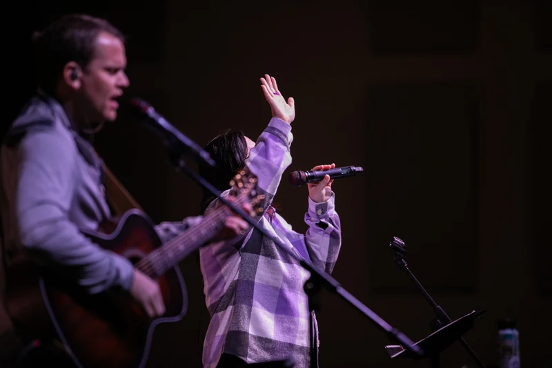 Worship at South Lakes Church, with a singer lifting her hand beside a guitarist.